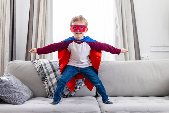 Boy in superhero costume on sofa