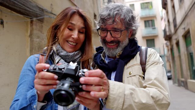 Married senior tourist couple looking photos on their camera during summer vacation. Elderly people and travel concept.