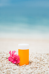Bright sunscreen bottle on pebble beach with sea as background. Concept of minimalist design of advertisement of sunscreen or cosmetics. Protection against ultraviolet rays or harmful effects of sun