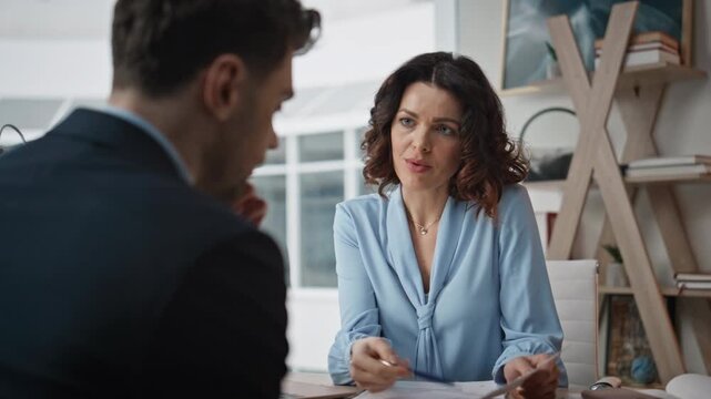 Businesswoman conducting job interview with elegant man at office desk closeup.
