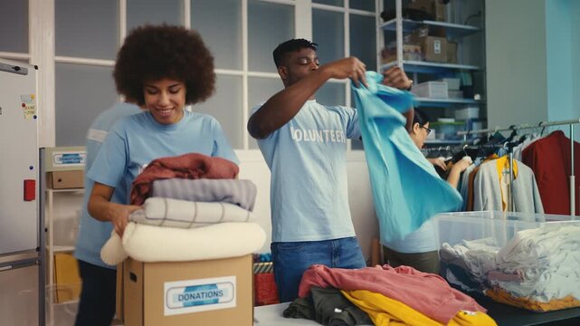 Multiethnic team of volunteers sorting donated clothes, packing items into boxes