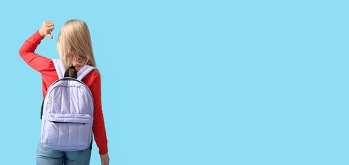 Little schoolgirl with backpack on blue background with space for text
