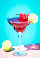 Raspberry margarita alcoholic cocktail drink with tequila, liqueur, lime juice, berry and ice. Blue background, hard light