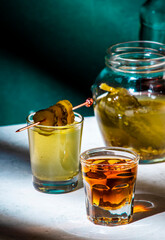 Pickleback, alcoholic cocktail made from cucumber pickle and whiskey in small shot glasses. Hard...