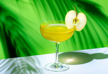 Yellow apple cocktail drink with vodka, gin, liqueur and syrup. on green background, hard light