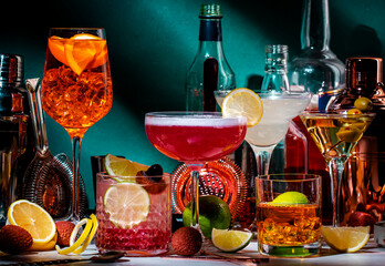 Cocktails. Strong drinks and aperitifs, bar tools, bottles on dark green background, hard light