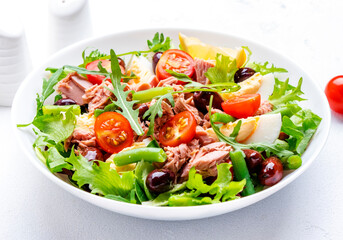 Tasty salad with tuna, tomatoes, eggs, beans, lettuce and olives on white background, top view