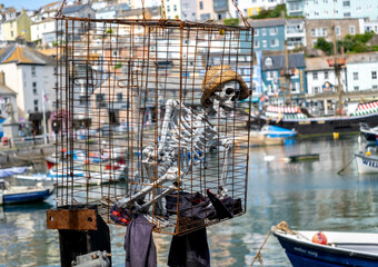 Plastic skeleton of a pirate in a metal cage on display in Brixham harbour