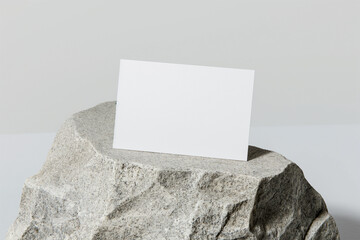 Horizontal business card mockup | white card on textured rock surface | minimalist design | light grey background | clean and simple composition | easily editable template | high-resolution