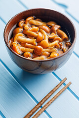 Pickled nameko mushrooms.Traditional japanese mushrooms in bowl on blue table.