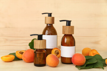 Bottles of cosmetic products with fresh apricots on wooden background