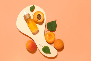Decorative podium with bottle of cosmetic oil and fresh apricots on orange background