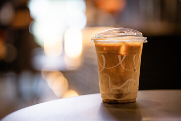 Close up and selective focus glass of ice latte on black table at coffee shop.