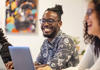 smiling man and woman in casual attire are sitting at an office desk with laptops, working together on digital marketing projects