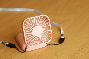Pink mini cooling fan close-up on wooden surface