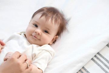 Cute little baby with mother lying on bed, closeup