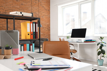 Interior of modern office with desks and shelf unit
