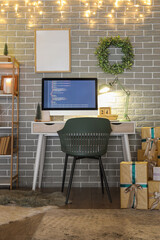 Interior of programmer's office with workplace, Christmas wreath and glowing lights