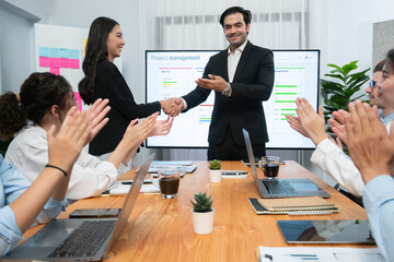 Cheerful meeting room, businesspeople celebrate with handshaking. Successful project was completed before the deadline. Business partnership and collaboration in project management. Habiliment