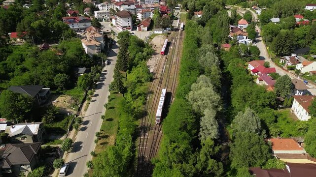 Aerial Drone Footage of a Train Approaching a Quaint Station of Slanic Romania Amidst Lush Trees &ndash; Scenic Journey Through Nature. Transportation concept seen from above. High angle shot.
