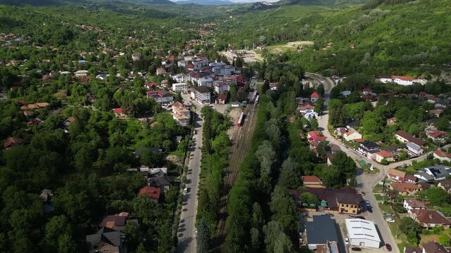 Aerial Drone Footage of a Train Approaching a Quaint Station of Slanic Romania Amidst Lush Trees &ndash; Scenic Journey Through Nature. Transportation concept seen from above. High angle shot.
