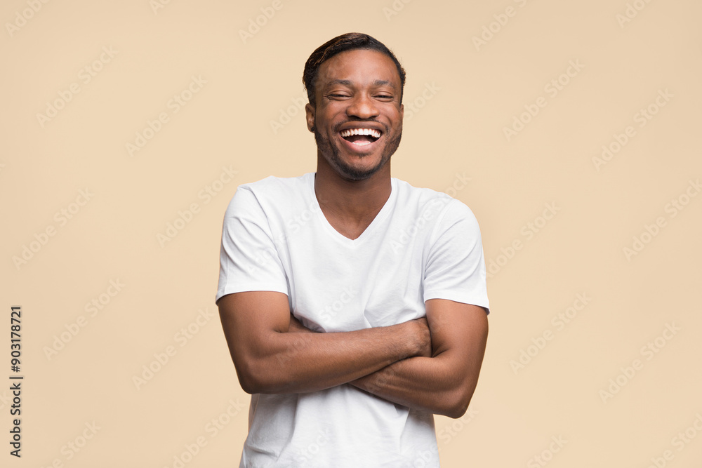 Wall mural Laughter. Positive Black Man Laughing Crossing Hands Looking At Camera Standing On Yellow Background. Studio Shot