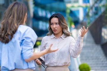 Two businesswomen arguing outdoors in modern office district. Concept of disagreement,...
