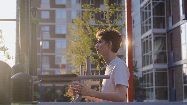 Young guy doing warm-up exercises before training on the sports ground