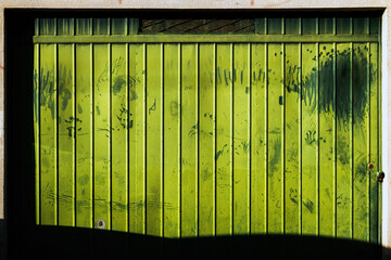 Old green worn metallic garage door as grunge background