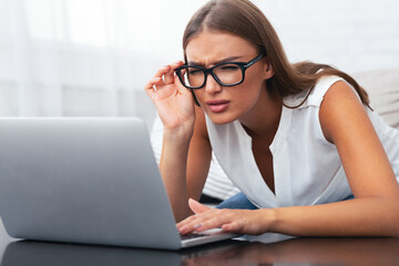 Eyesight. Young Woman Looking Through Eyeglasses At Laptop Having Near Vision Problem Sitting On...