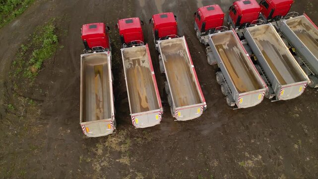 Aerial footage of tipper trailer truck used to haul bulk gravel sand and materials at a fracking mining, drilling extraction and construction worksite. Drone shot of vehicles building a fracking well.