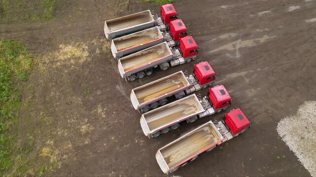 Aerial footage of tipper trailer truck used to haul bulk gravel sand and materials at a fracking mining, drilling extraction and construction worksite. Drone shot of vehicles building a fracking well.