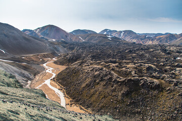 Hiking up the sulphur peak with views of old lava remains and river meandering through in Landmannalaugar in Iceland