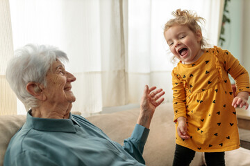 Senior Caucasian woman playing with her toddler great granddaughter at home. Playful family moments