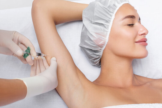 Aesthetic cosmetologist making lipolytic injections to burn fat on the arms of young woman. Female aesthetic cosmetology concept