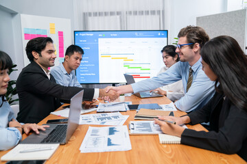 Cheerful meeting room, businesspeople celebrate with handshaking. Successful project was completed...