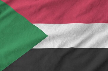 Sudan flag depicted on folded wavy fabric of old cloth close up