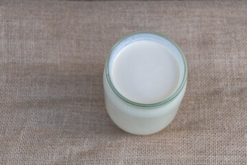 Top view of glass jar with milk on burlap background