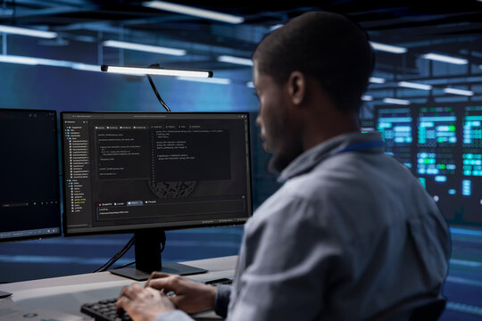 Software developer reconfiguring server farm to optimize it for data processing requirements of customers. African american man ensuring data center equipment operates efficiently