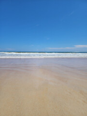 A peaceful beach with gentle waves and a clear blue sky