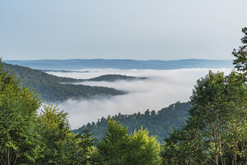 Stuning morning fog over mountain valley showing cloud covered mountain tops, summer background, natural authentic