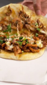 vertical video, showing the inside of a taco al pastor called gringa