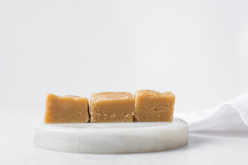 peanut butter fudge on a marble tray, soft peanut fudge squares stacked on a white tray