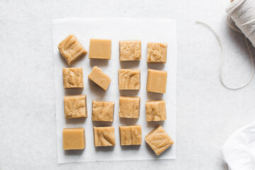 Overhead view of peanut butter fudge on a white marble tray, top view of soft peanut fudge squares on a white background