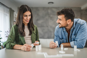 couple boyfriend and girlfriend play dominoes at home and have fun