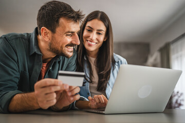 adult couple buy online on laptop with credit card at home