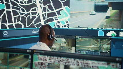 Operator uses satellite navigation map to guide delivery truck drivers, works in observation room...