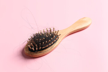 Wooden brush with lost hair on pink background