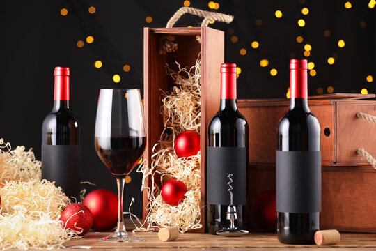 Bottles of wine, glass, wooden boxes, corks and red Christmas balls on table