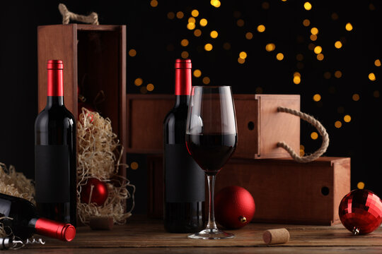 Bottles of wine, glass, wooden boxes, corkscrew and red Christmas balls on table